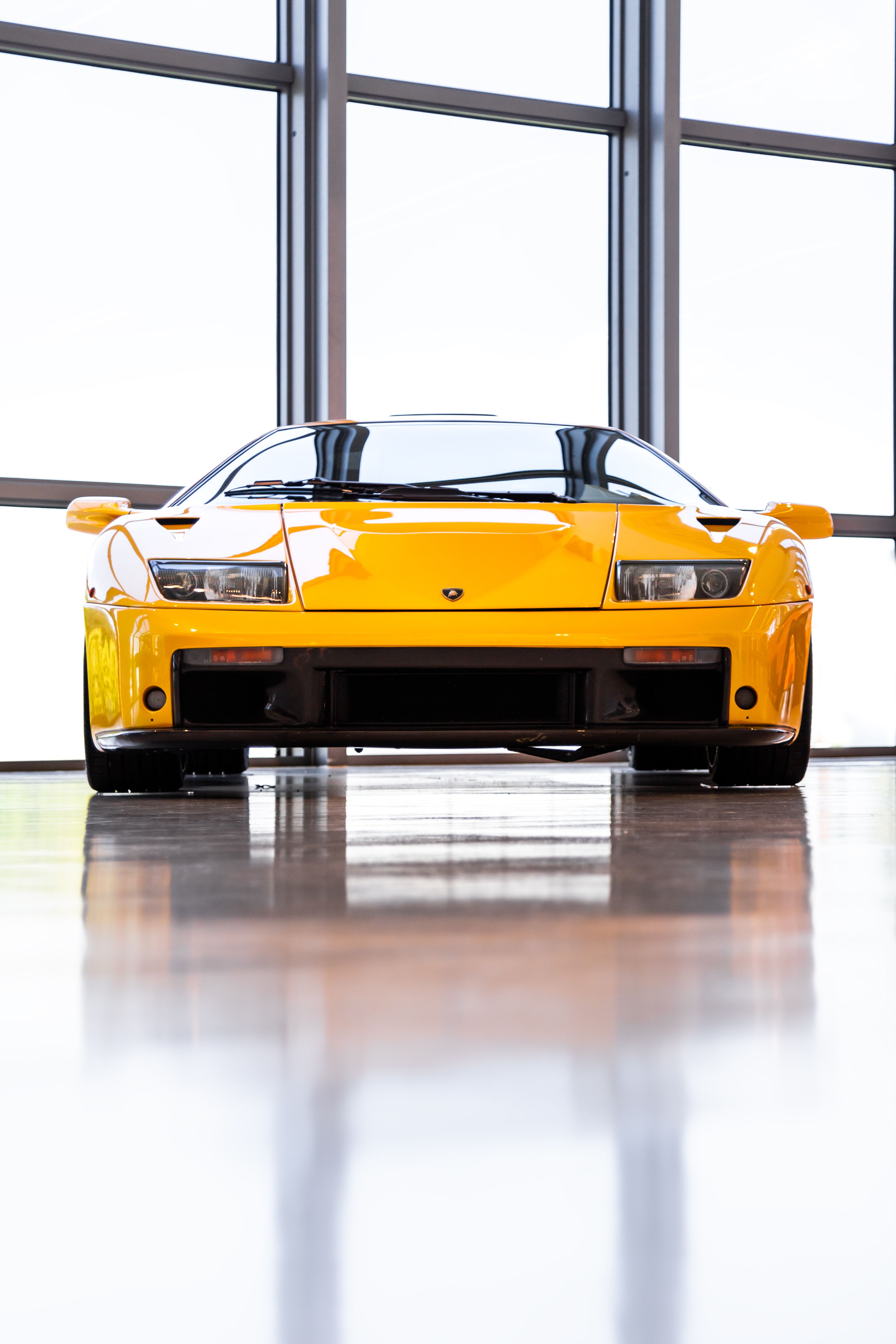 Yellow Lamborghini Diablo photographed head-on in a bright showroom