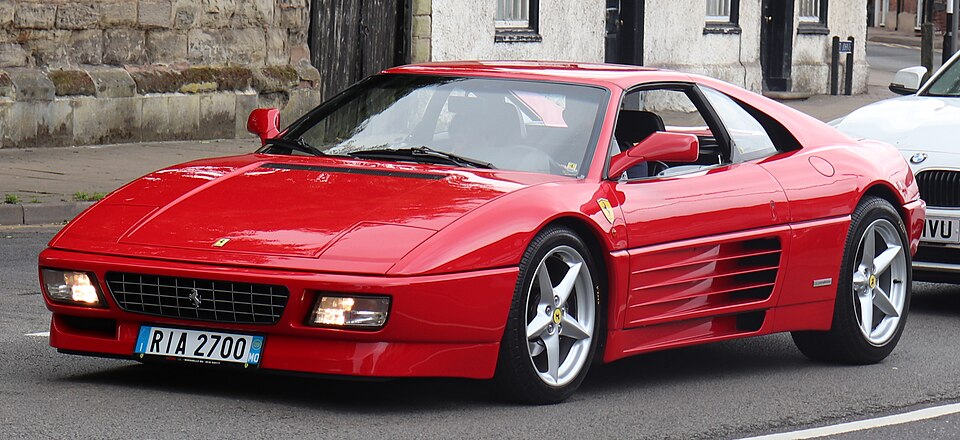 Red Ferrari 348 TS seen from the front and side, showing its horizontal side strakes.